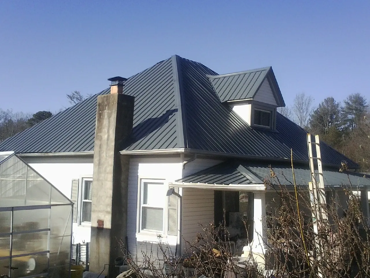 Dark blue standing seam metal roof on a white farmhouse with dormer — Slate & Tile Roof Repair by Roofing Brothers in Honesdale