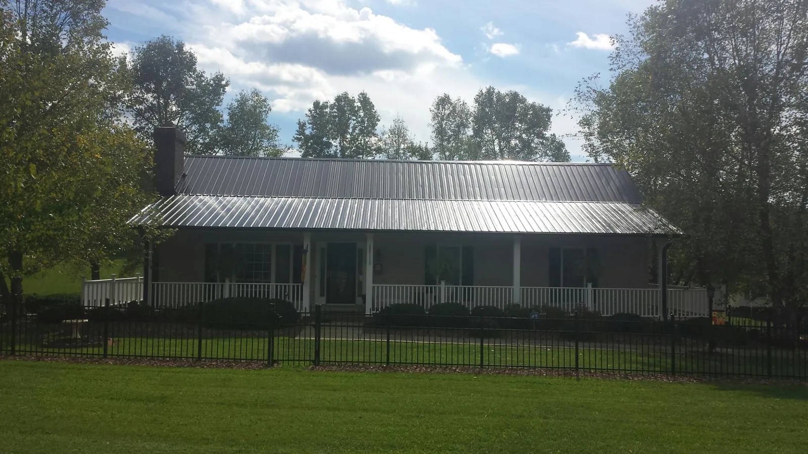Gray metal roof on a brick ranch with a full width front porch — Gutter Guard Installation work by our crew in Honesdale