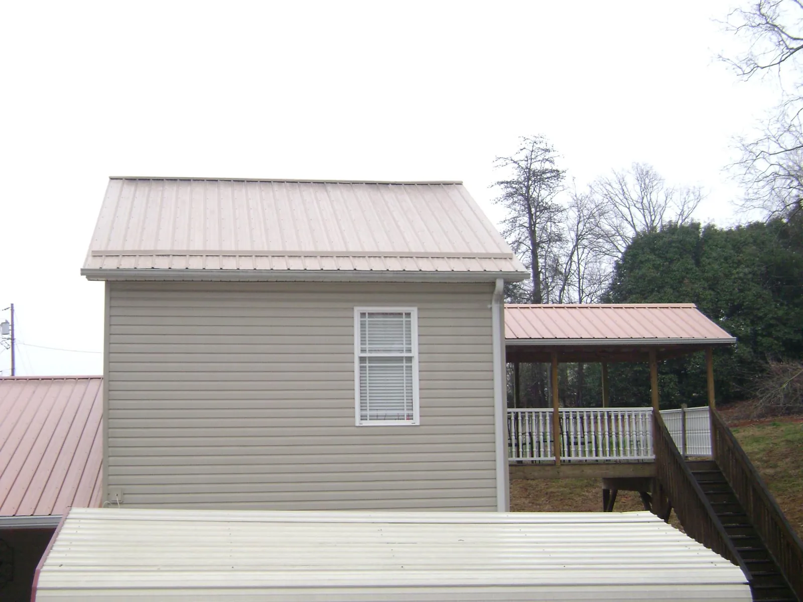 Tan metal roofs on a two story addition and attached porch, from a Roof Replacement job in Honesdale