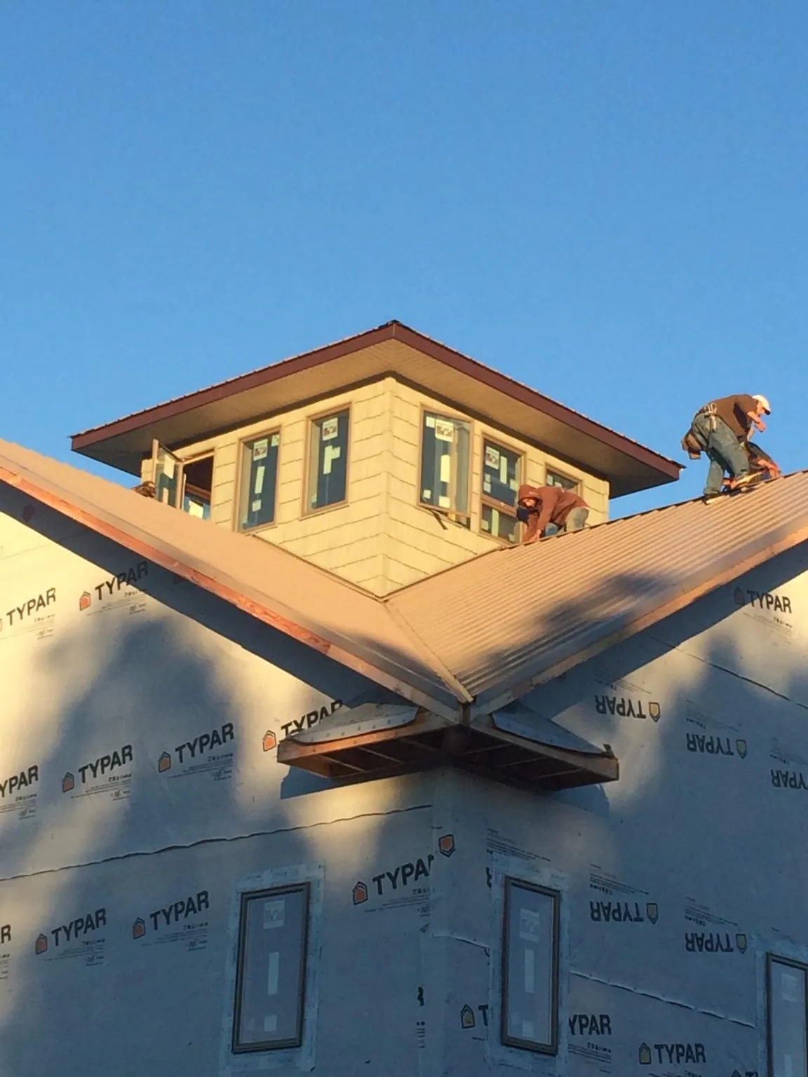 Roofers working around a rooftop cupola on a new metal roof at sunset — Roof Waterproofing in Honesdale by Roofing Brothers